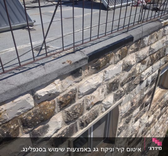 קיר אבן עם חלונות וסורגים על גג שטוח